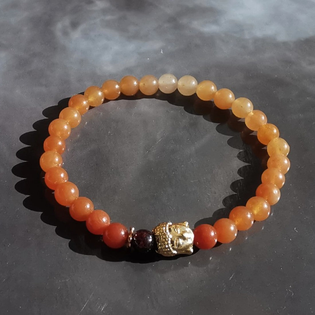 Création originale "ANAMOUR-bijoux".  Ce bracelet est monté un fil élastique de bijoutier ( très résistant) avec des perles en:  Aventurine rouge,  grenat.  Tête de bouddha et autres apprêts en plaqué or 18 k.  Les pierres sont 100 %naturelles, non traitées.