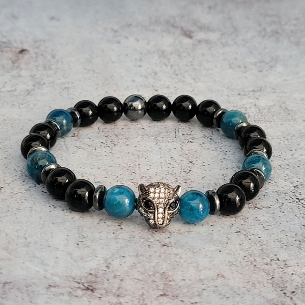 Ce bracelet est réalisé à la main avec des pierres naturelles d'onyx et d'apatite bleue. La tête de léopard qui trône au centre de ce bracelet représente la puissance spirituelle de l'animal sauvage, symbole de liberté, de force et de détermination.